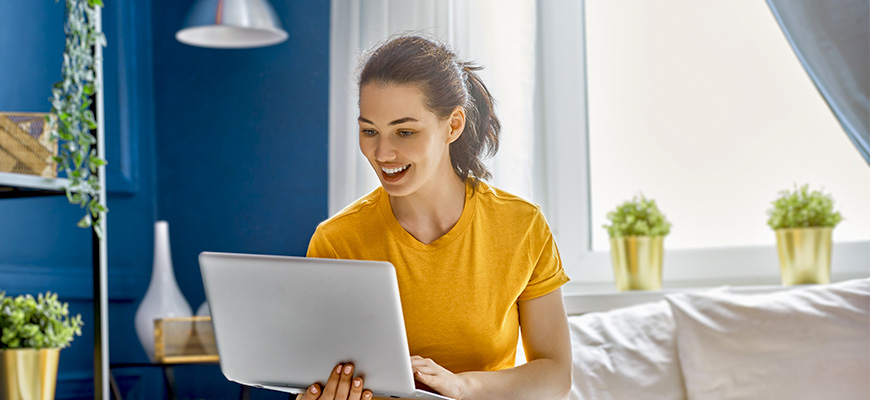 5 things improve your credit score - blog image - woman in yellow smiling at computer
