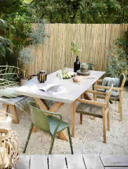 Bamboe schutting naturel achter tuintafel met gekleurde stoelen