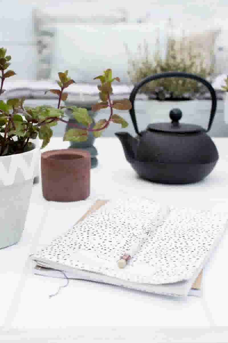 wit betegelde tafel met plantje, schrift en zwarte theepot
