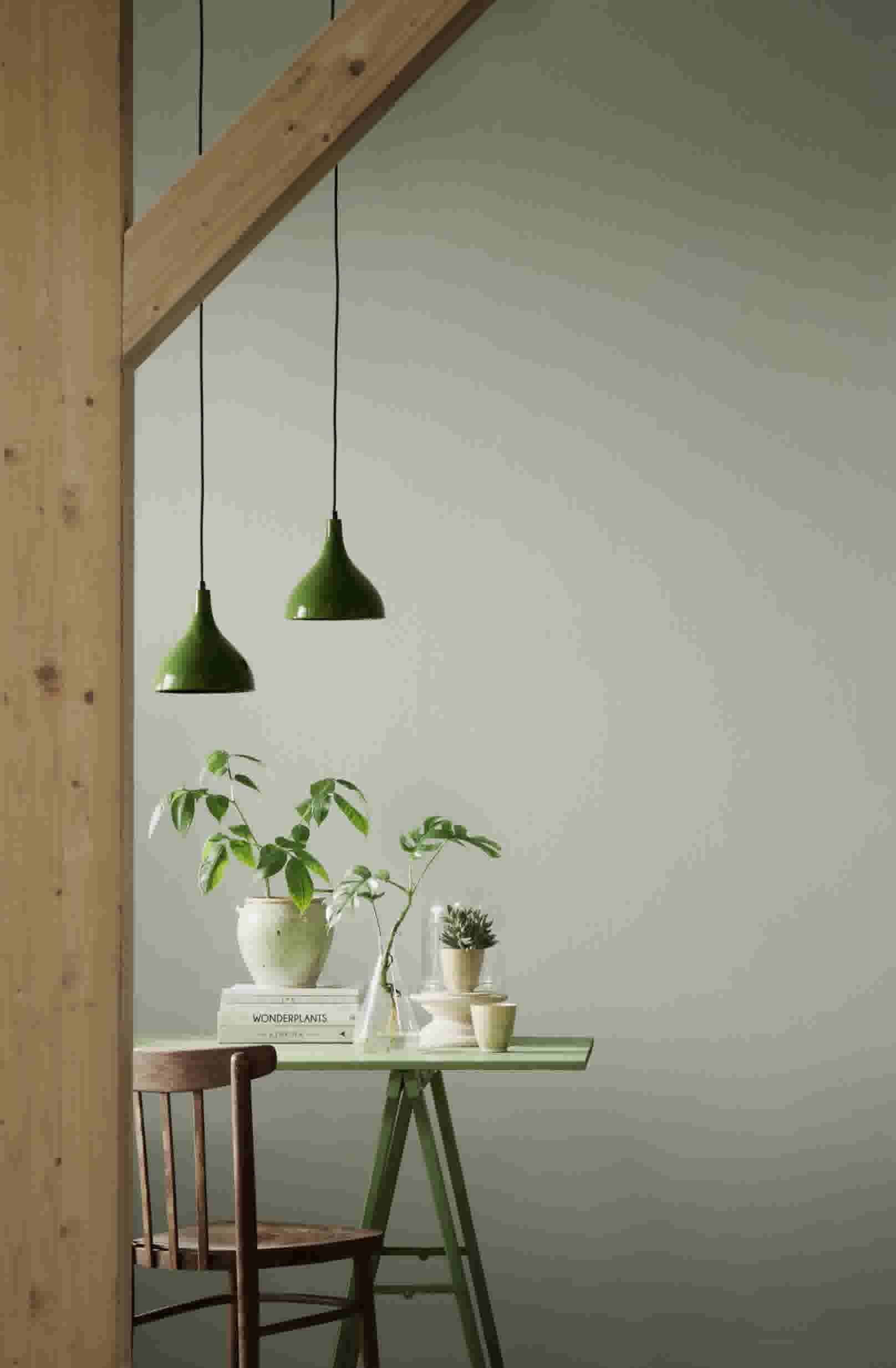 Nordic green als kleur op de muur achter een groene tafel met houten stoel