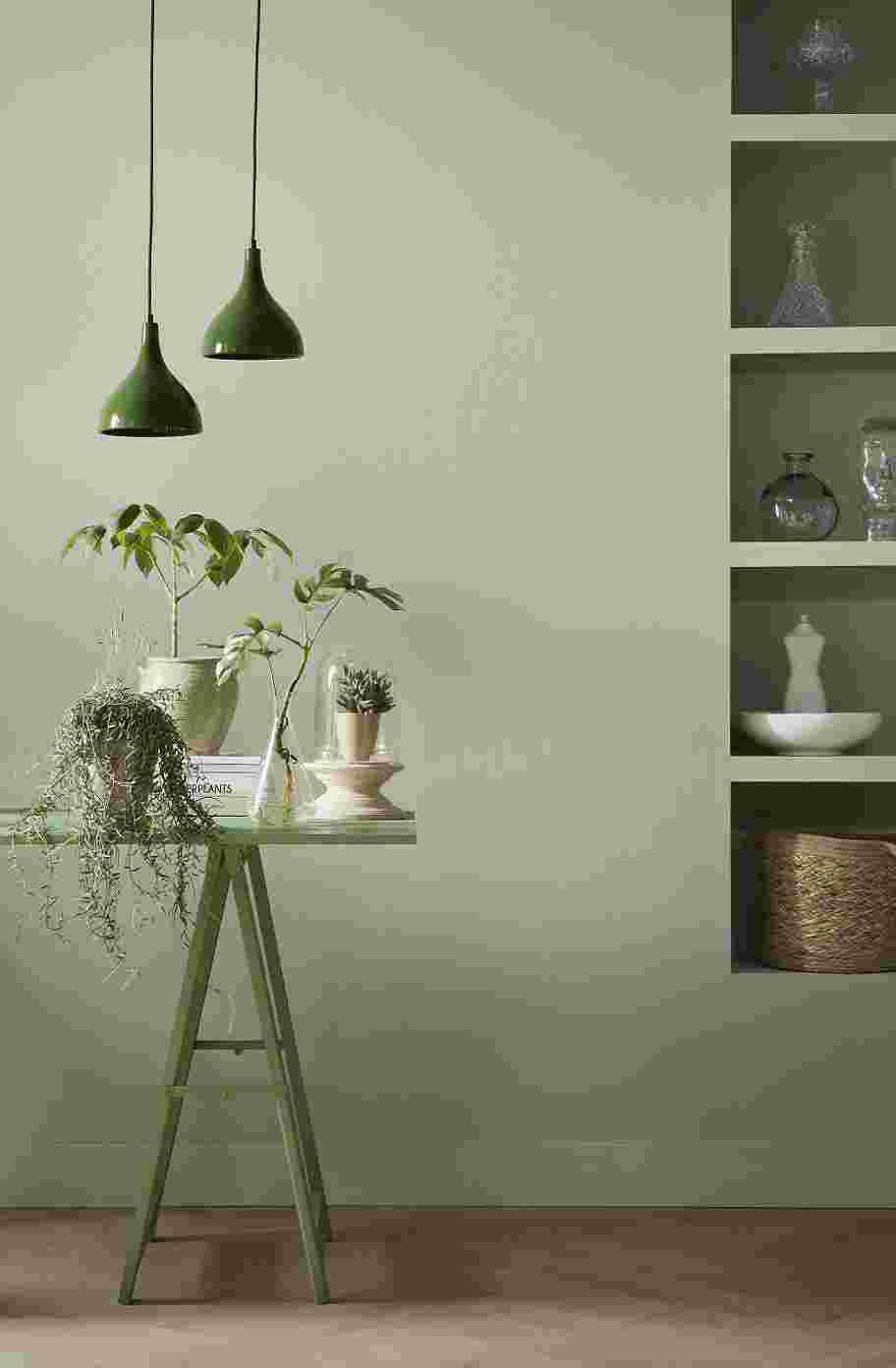 Grijsgroene muur met donkergroene lampen en een tafel met planten