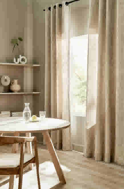 Halfopen zandkleur gordijnen hangend in een beige interieur met houten tafel en stoel