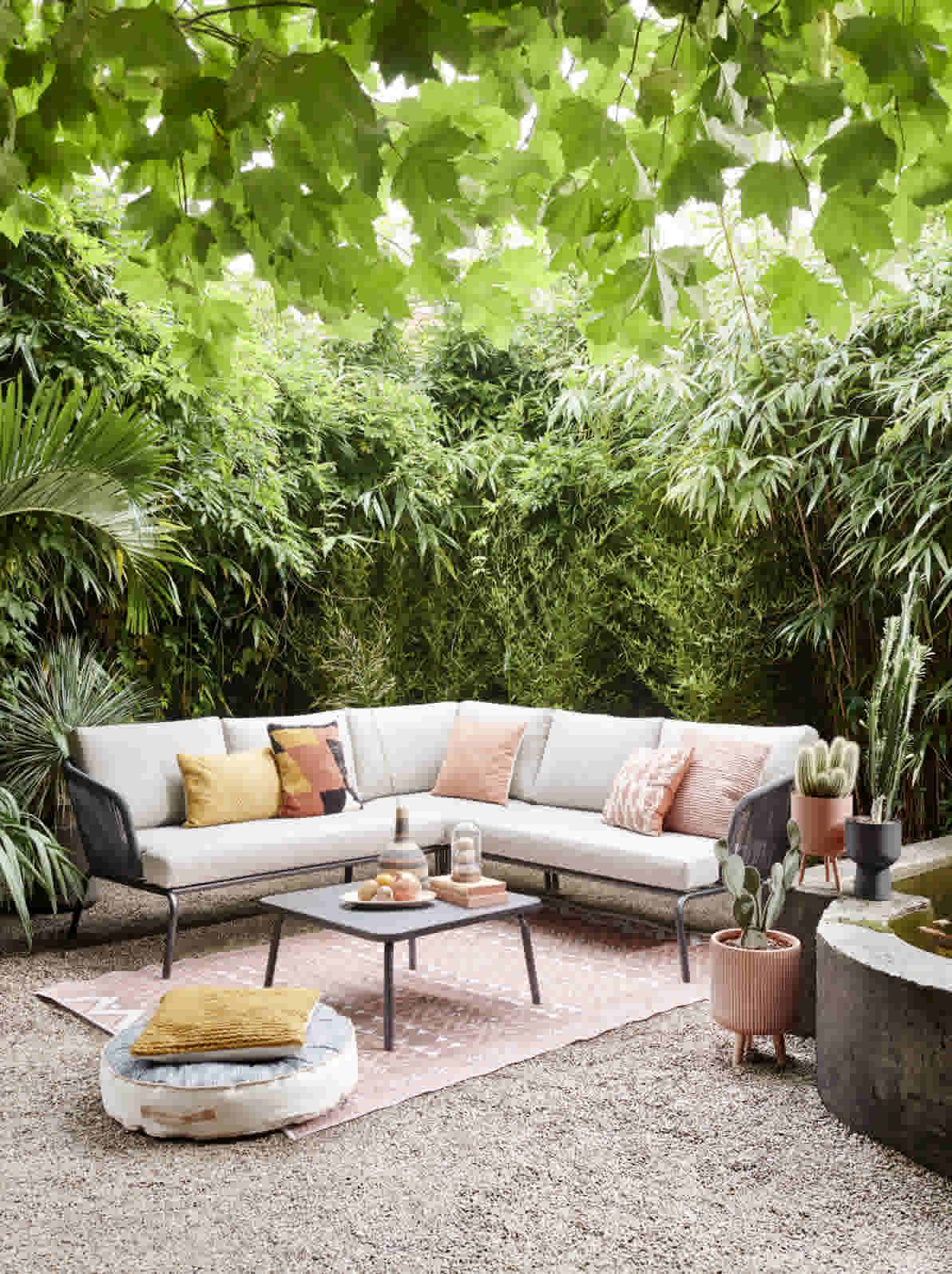 Loungebank tuin met witte kussens en kleurrijke sierkussens