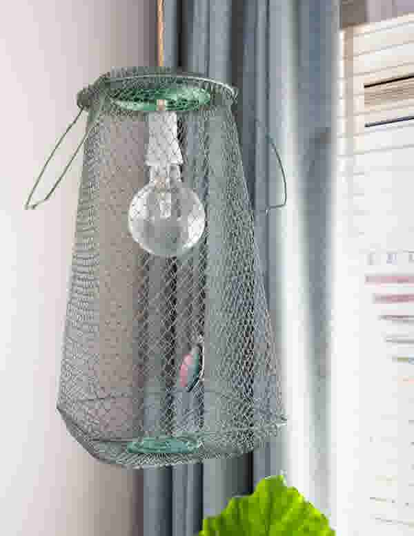 Hangende visnet lamp voor een raam met open gordijnen