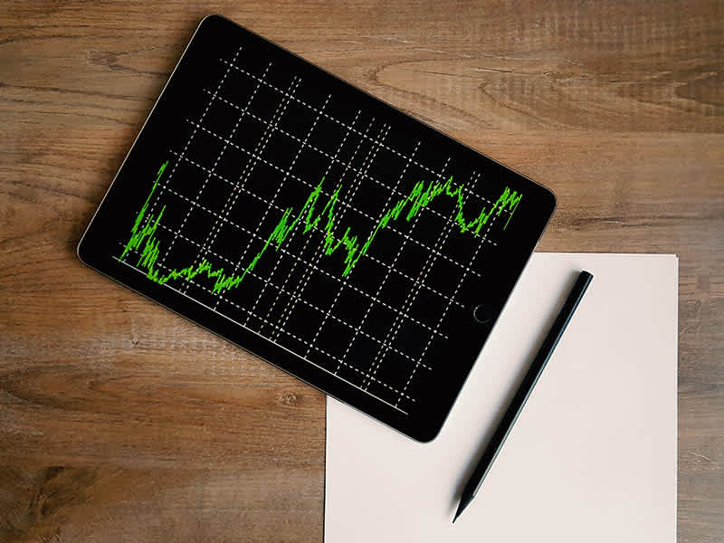 An image of a tablet with an graph and a pen and paper