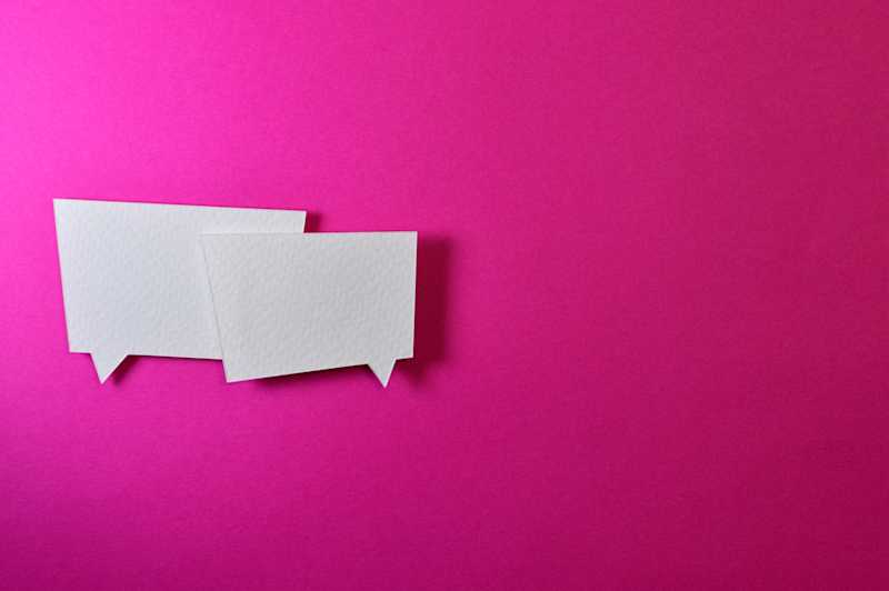 Two paper speech bubbles on a pink background.