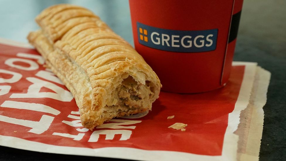 A Gregg-s vegan sausage roll next to a drink