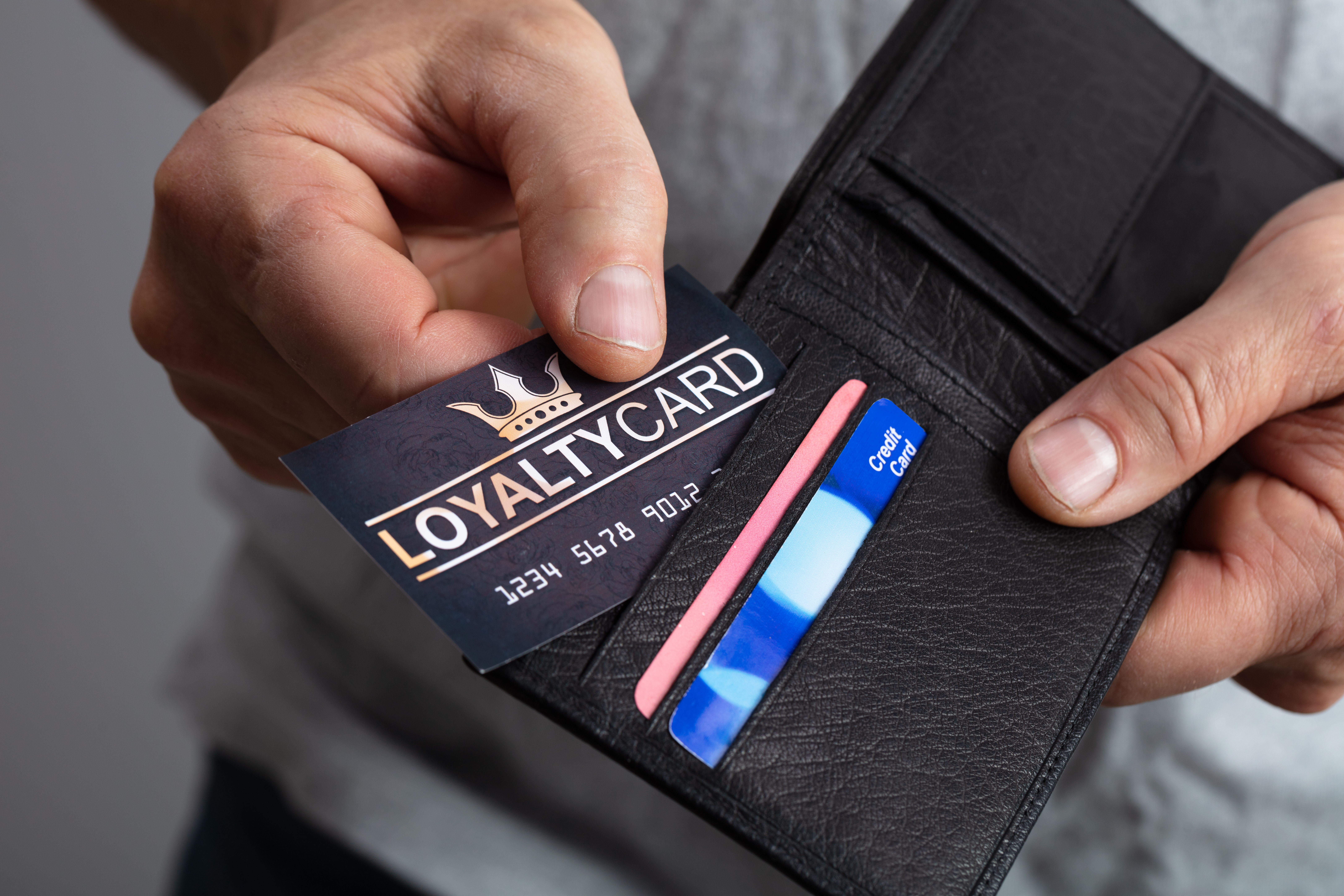 A close-up hand taking a loyalty card out of a wallet. Loyalty programs are a way brands engage with their loyal customers.