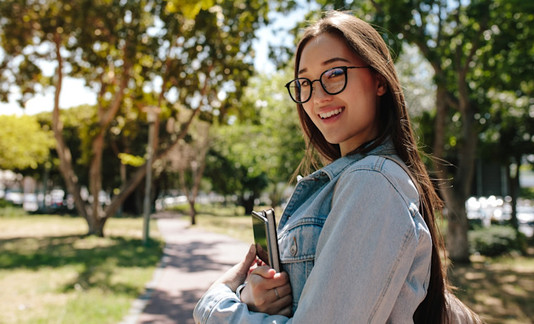 A female test taker wearing denim shirt walks in a park
