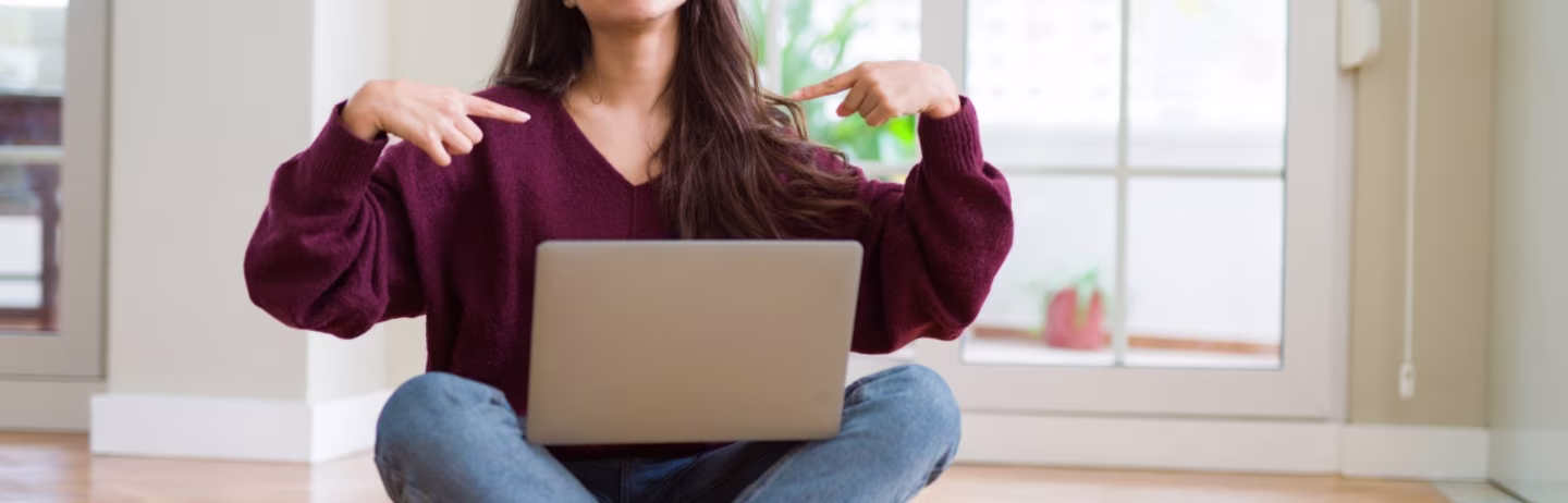 Female IELTS test taker in red full-sleeve t-shirt points her finger at her laptop