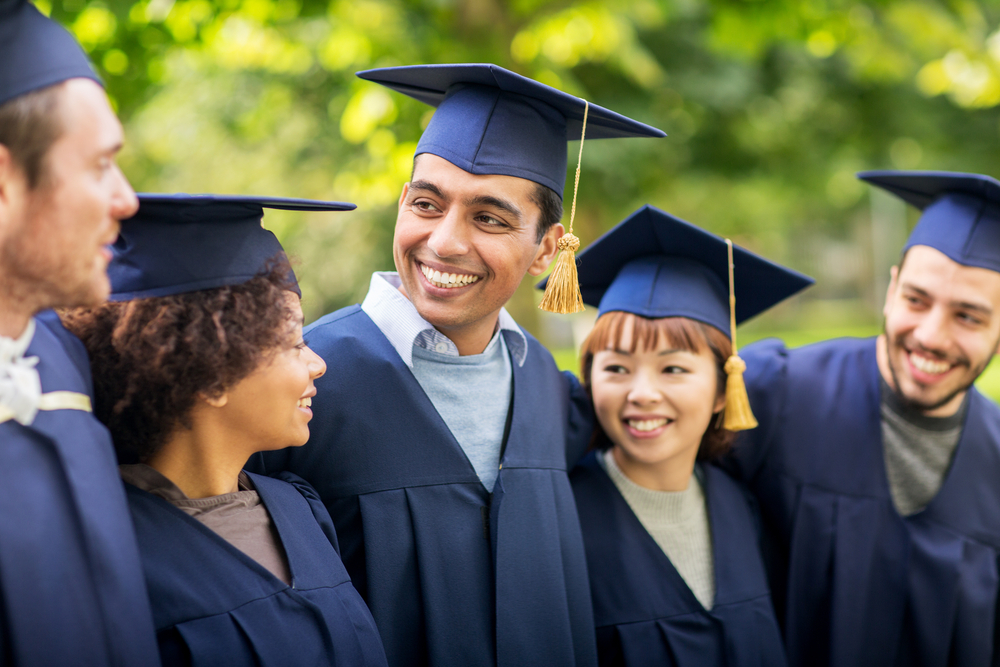 Five test taker wearing graduation grown and smiling at each other