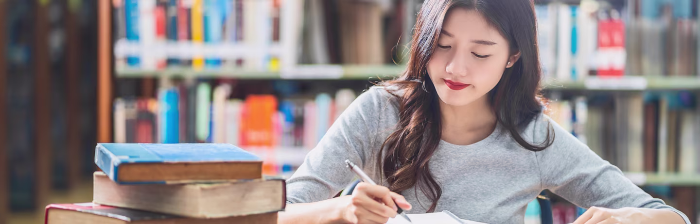 Female IELTS test taker wearing a grey t-shirt preparing for the IELTS test with official preparation materials