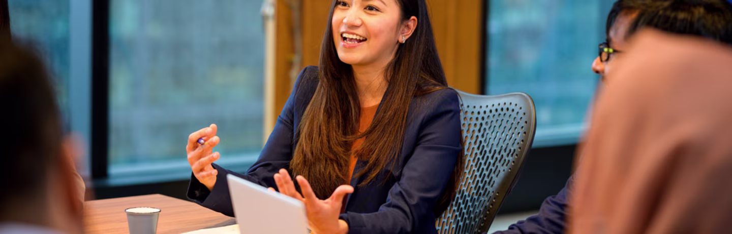 People sit around a conference table with a laptop to verify IELTS One Skill Retake results online