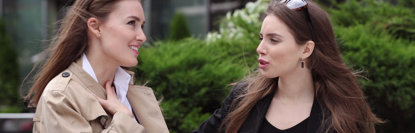 A man wearing a blue shirt and a woman wearing a pink sweater stand on the bank of East River in New York City