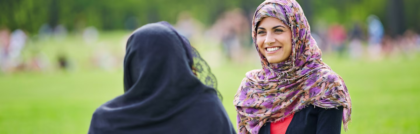 两名戴着头巾的女考生在公园里愉快地交谈。