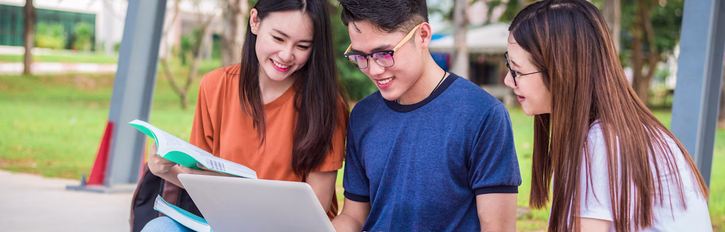 A male test taker and a female test taker in casual attire looking at a laptop and prepares for IELTS.