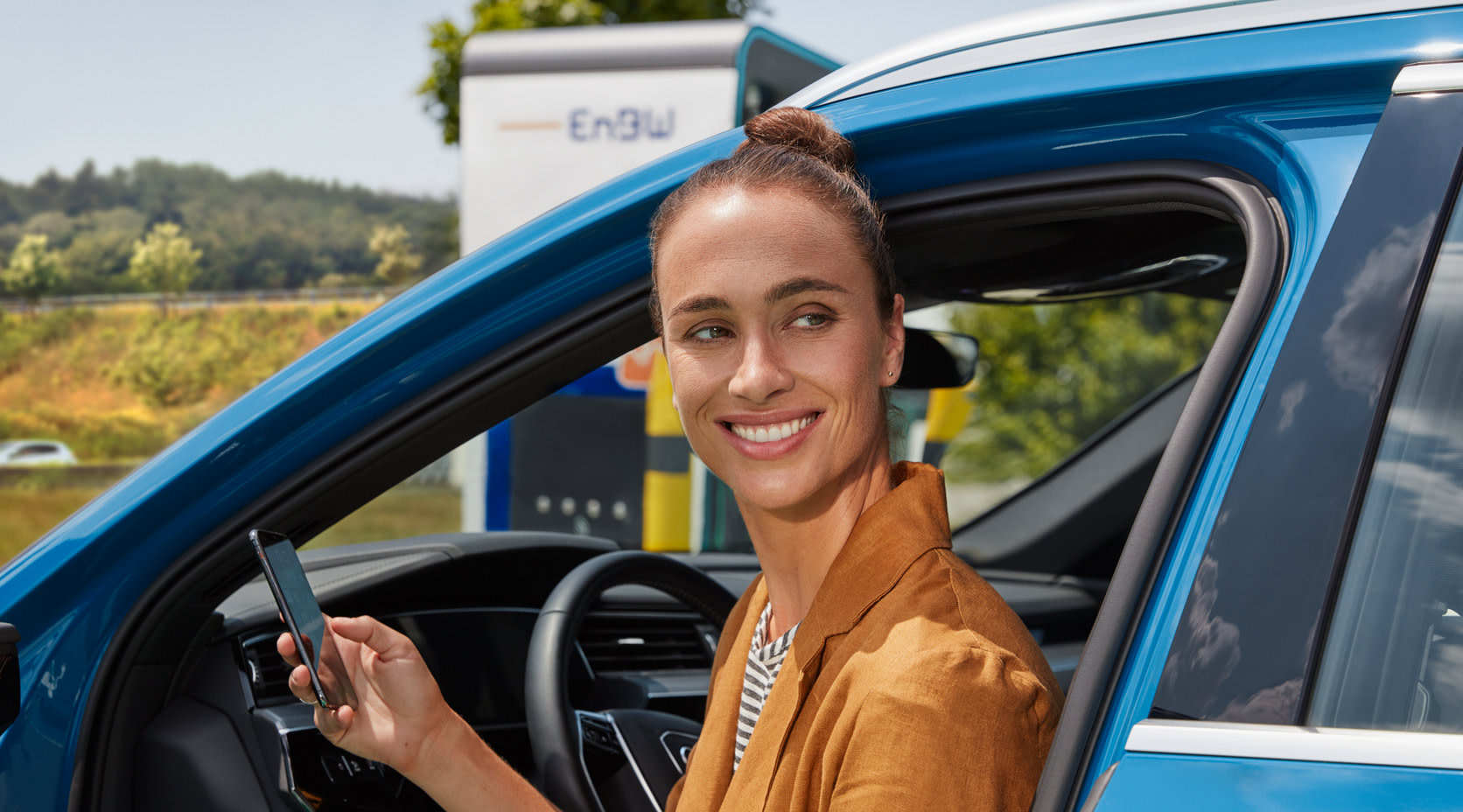 Junge Frau lädt E-Auto über EnBW mobility+ App