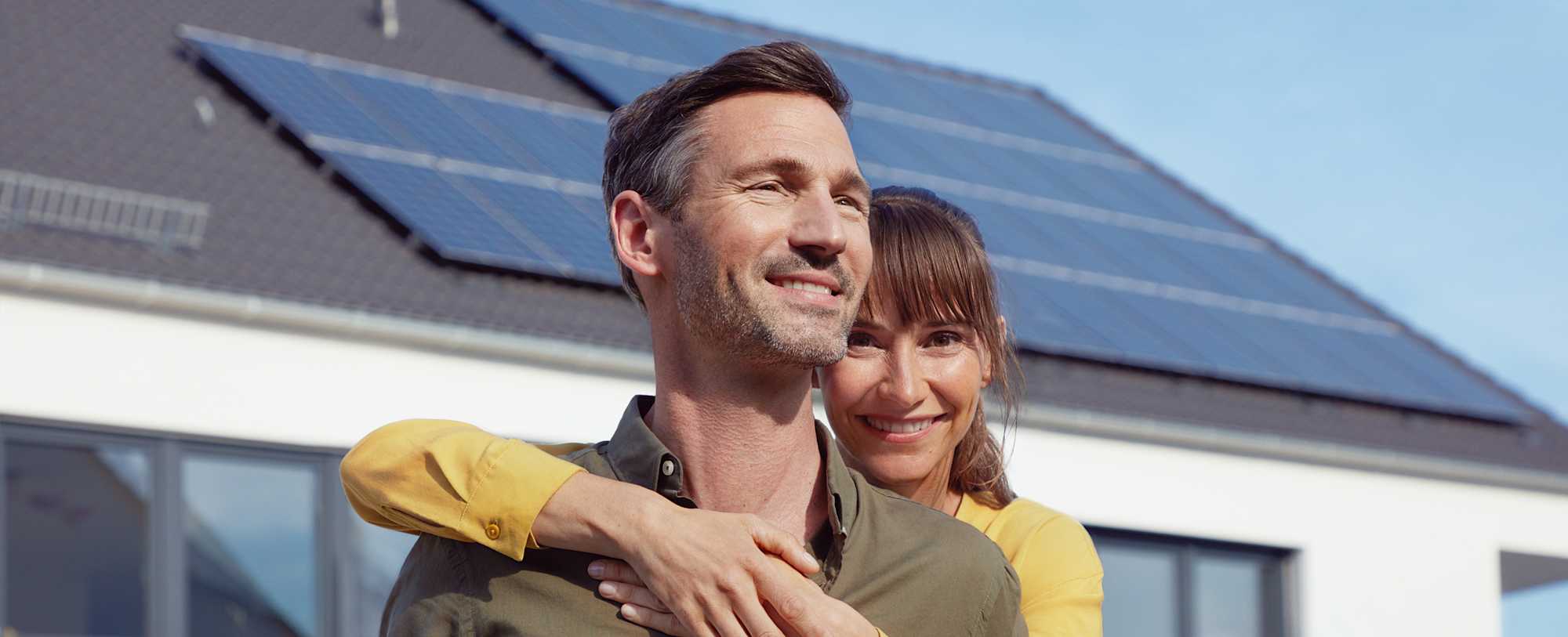 EnBW Kunde Daniel mit seiner Frau, im Hintergrund sein Haus mit EnBW solar+ Solaranlage