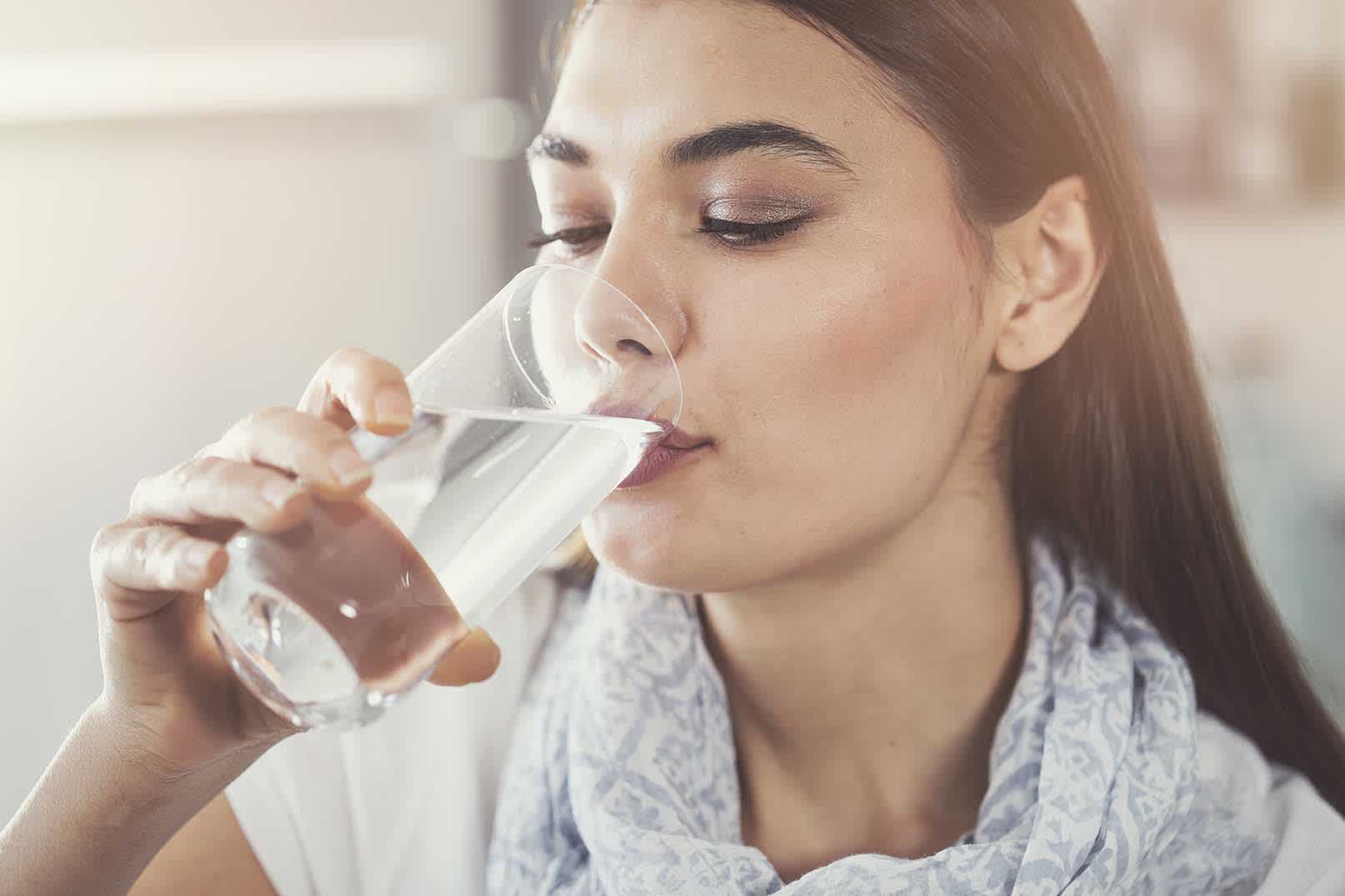 Frau trinkt Wasser aus einem Glas