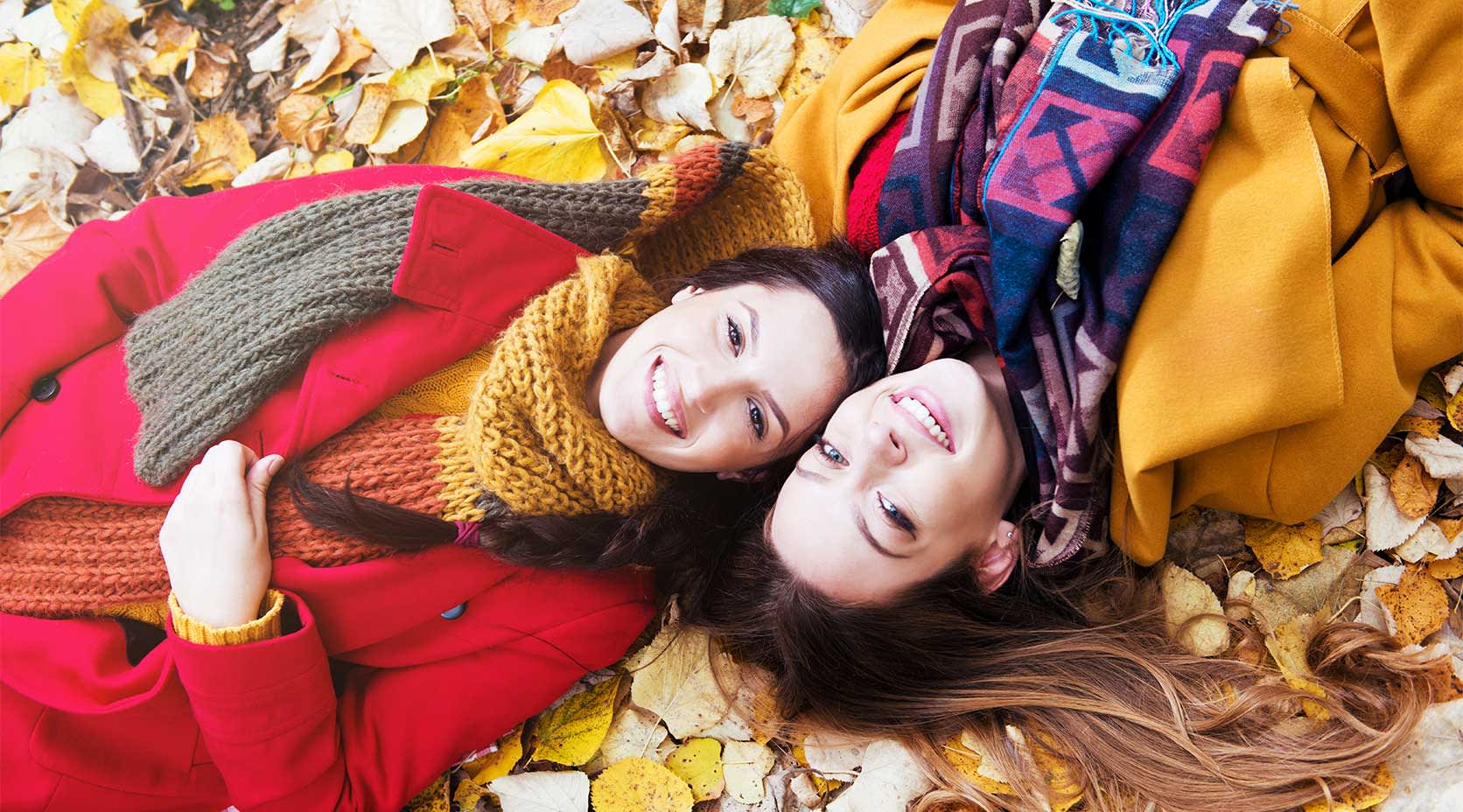 Zwei junge Frauen liegen auf Herbstlaub