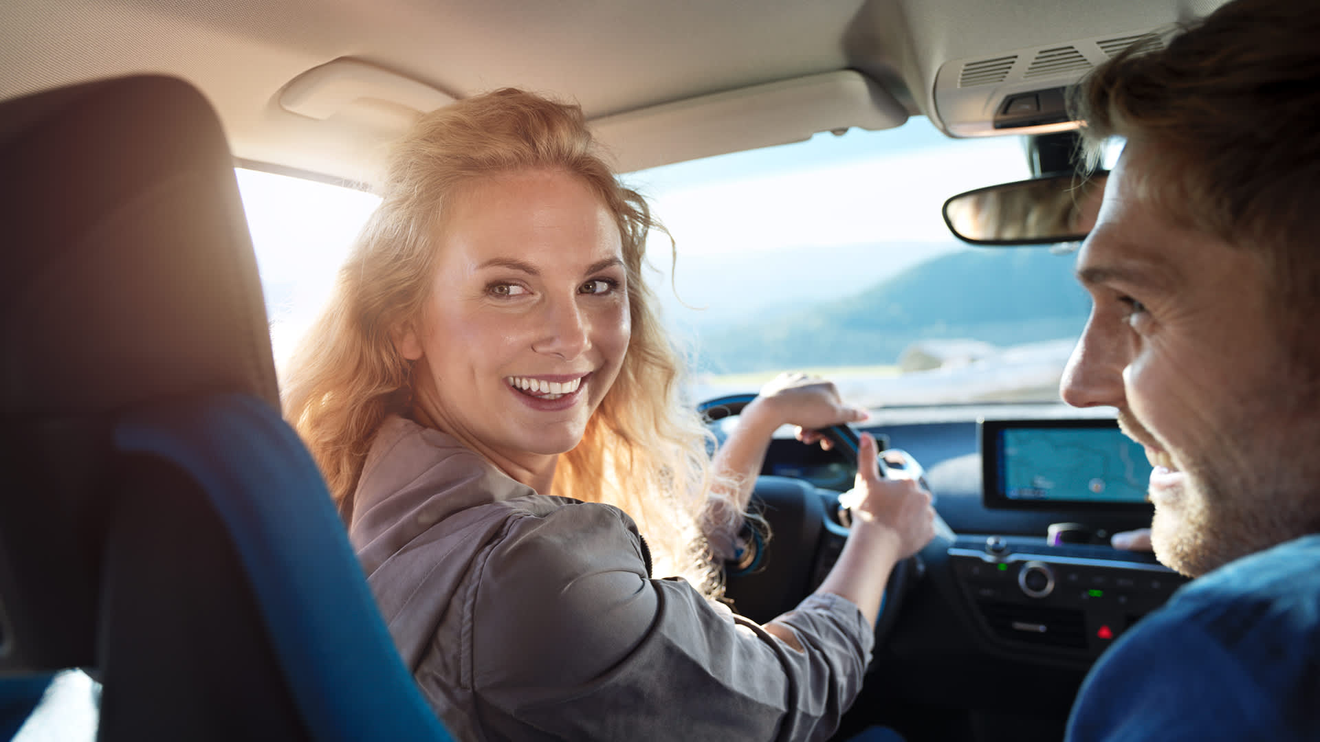 Junges Paar ist gut gelaunt im Elektroauto unterwegs