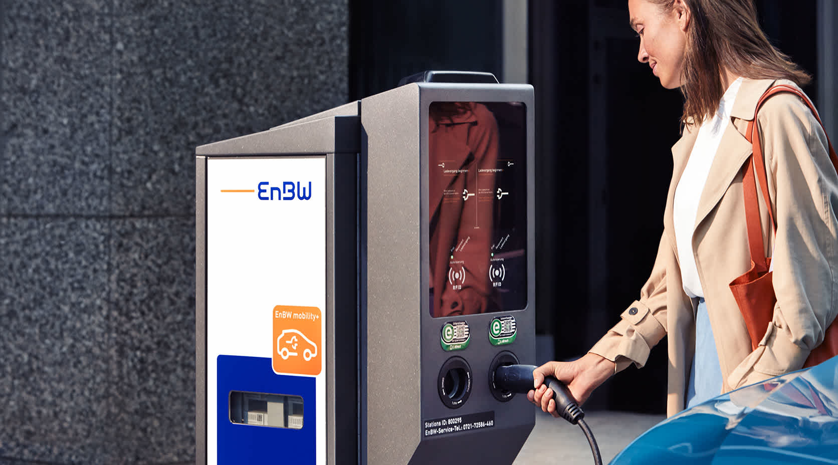Frau beim Laden Elektroautos in der Stadt