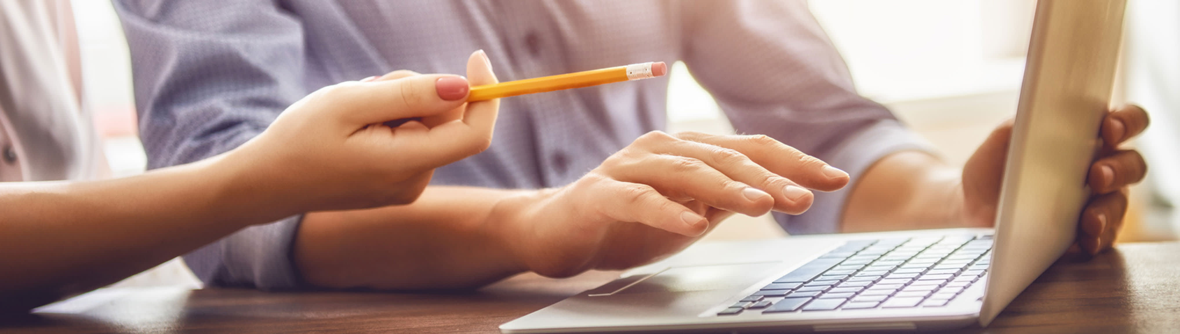 Frau zeigt mit Stift auf Laptop