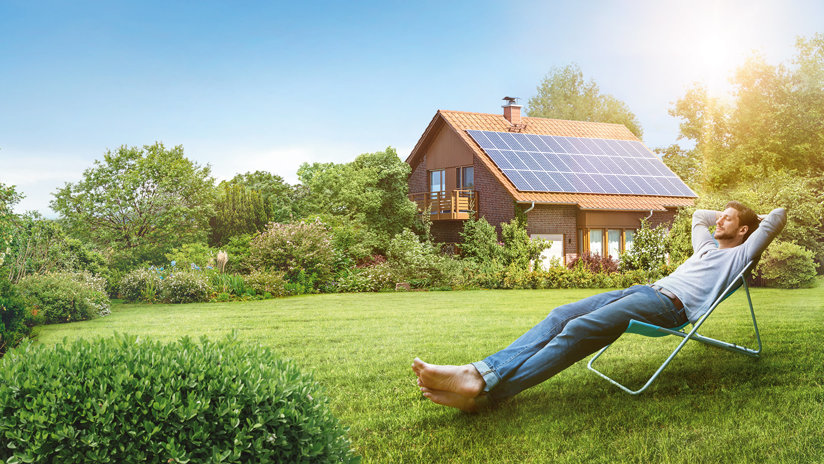 Mann entspannt vor Haus mit Solaranlage auf Dach
