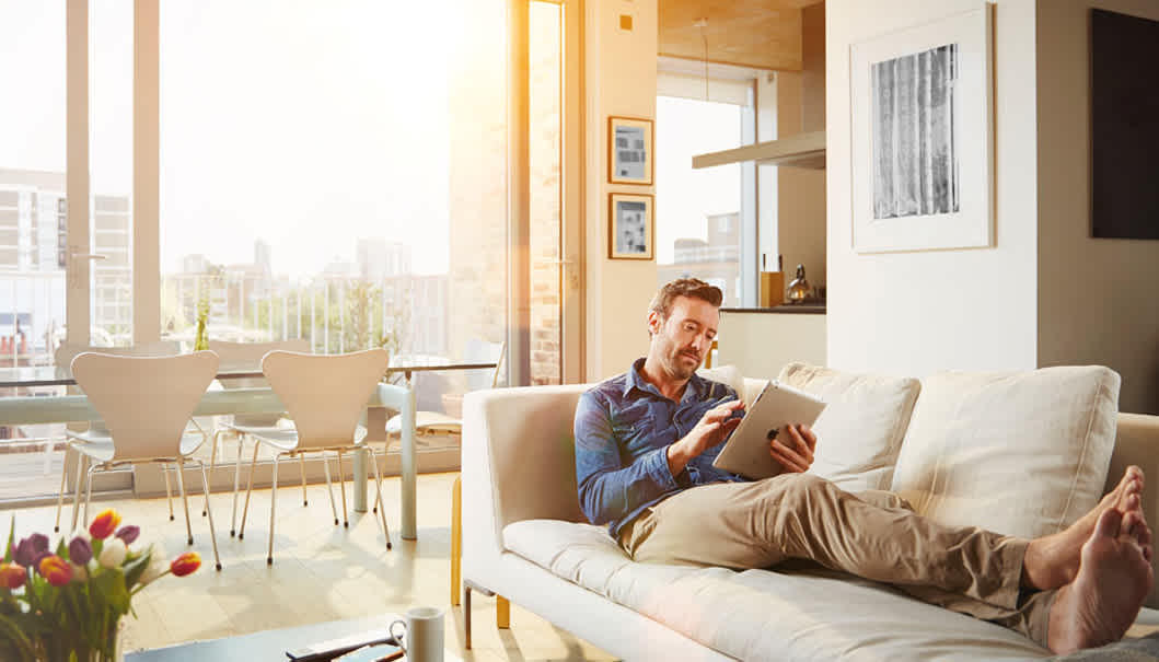 Dank EnBW Secure: Mann mit Tablet sitzt entspannt auf der Couch