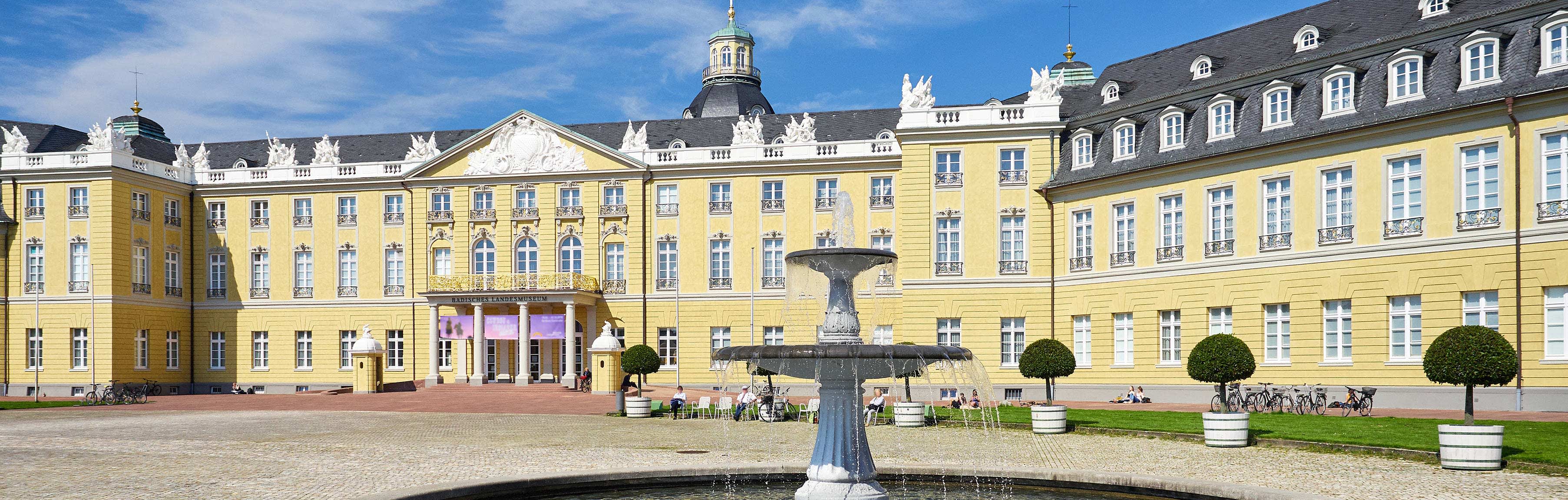 Ansicht des Schlosses in Karlsruhe mit Brunnen im Vordergrund
