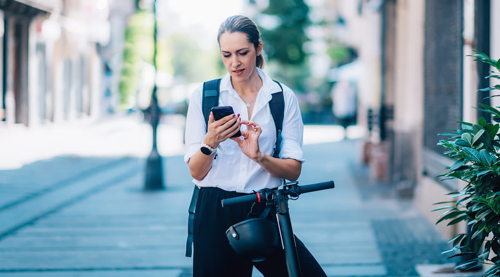 Frau mit Handy und E-Scooter in einer Smart City