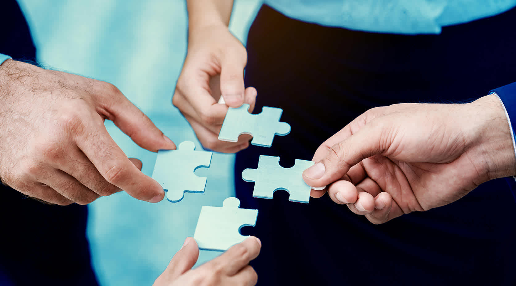Vier Menschen setzen Puzzleteile zusammen