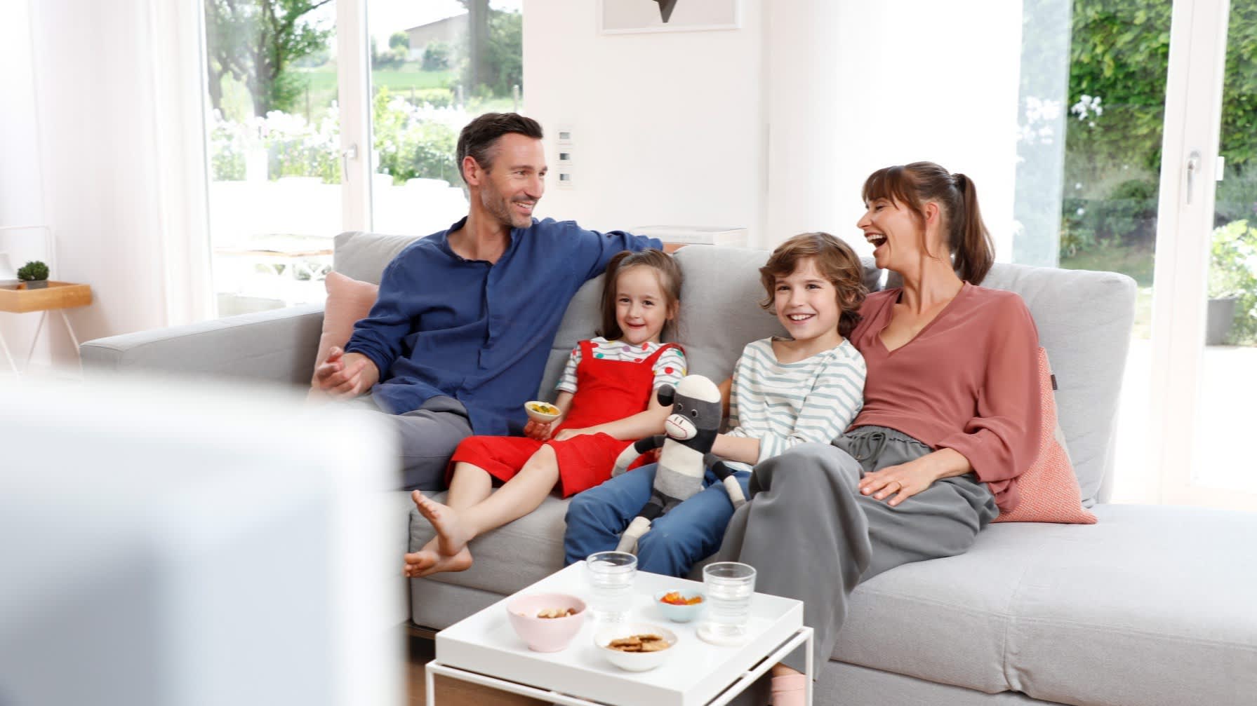 Eltern sitzen mit ihren zwei Kindern auf dem Sofa