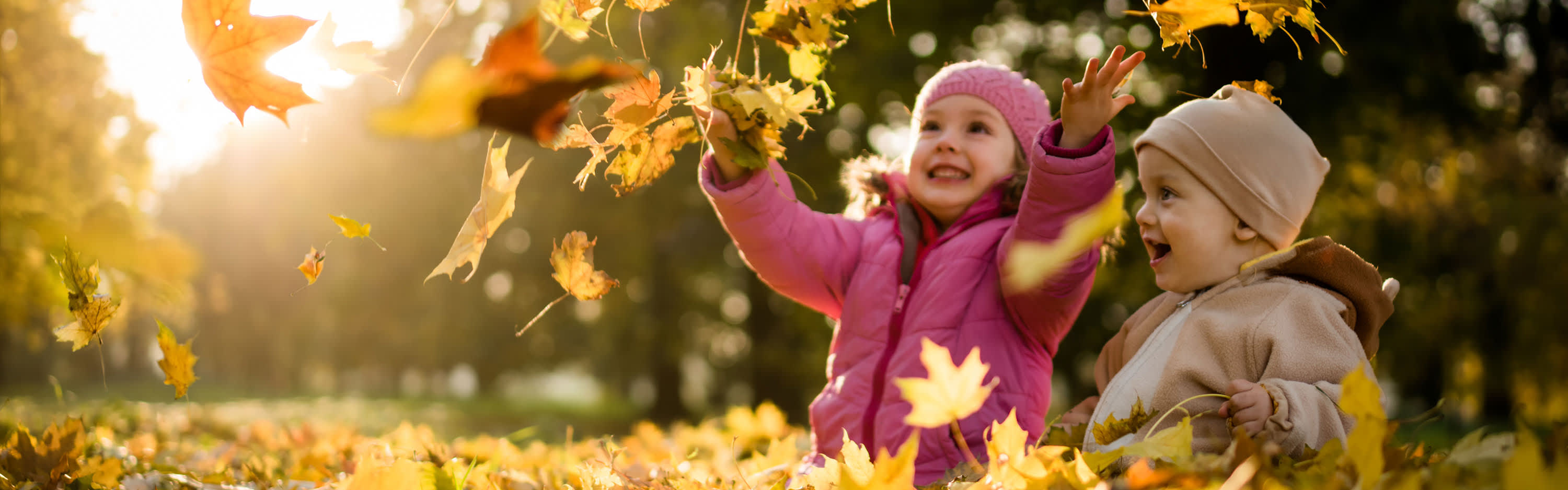 Kinder spielen mit Laub im Herbst