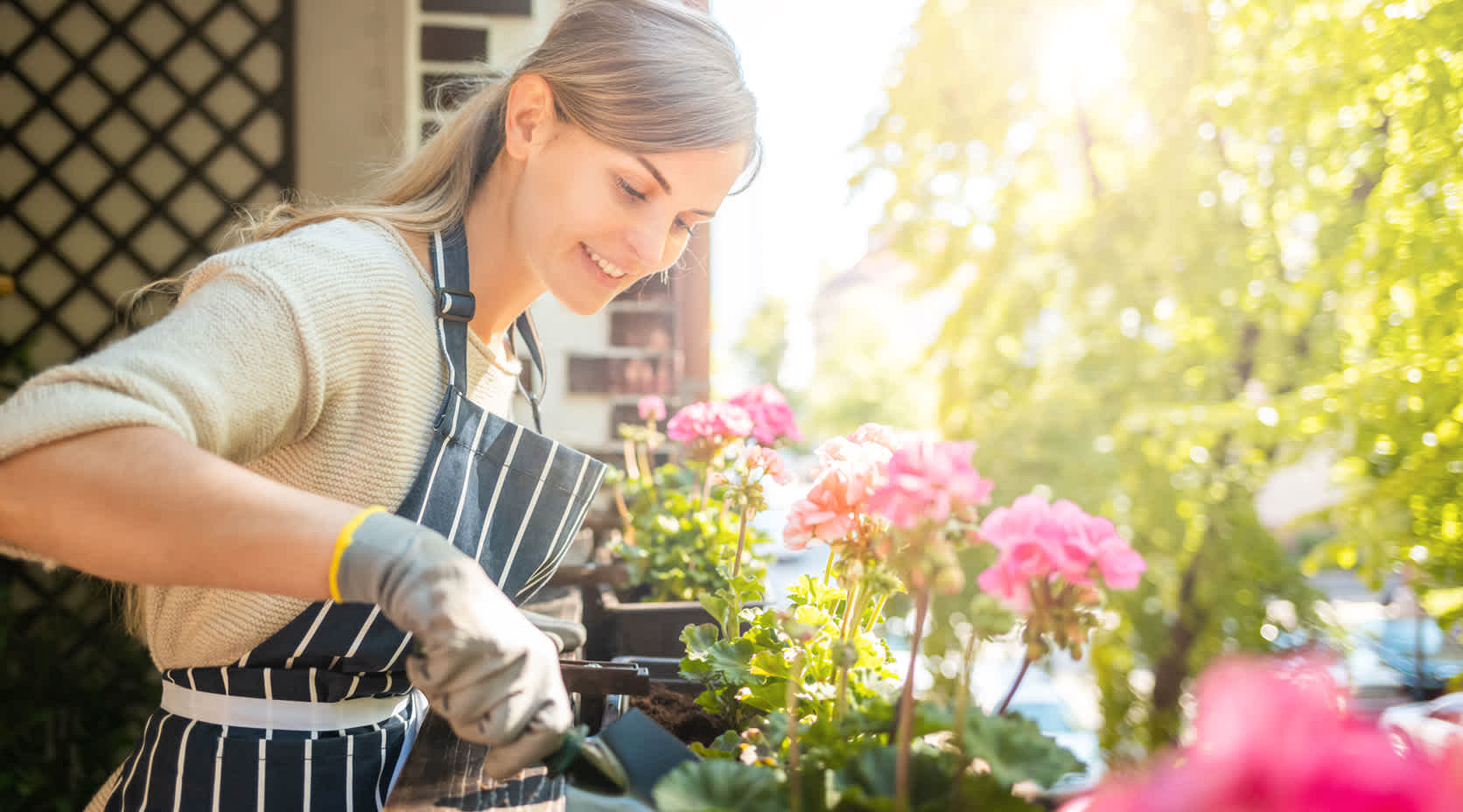 Frau pflegt Blumen am Balkon