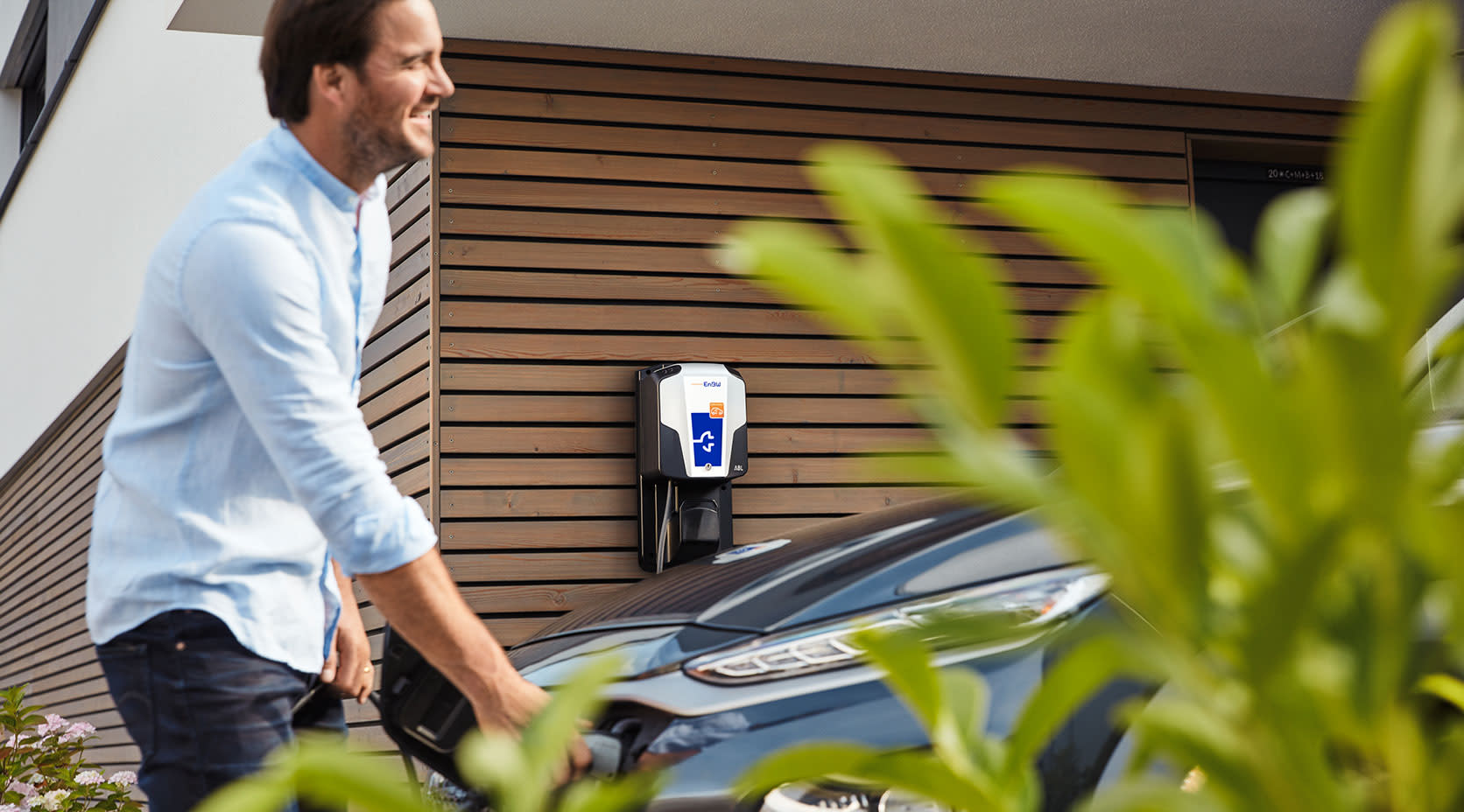 Mann lädt Elektroauto Zuhause auf