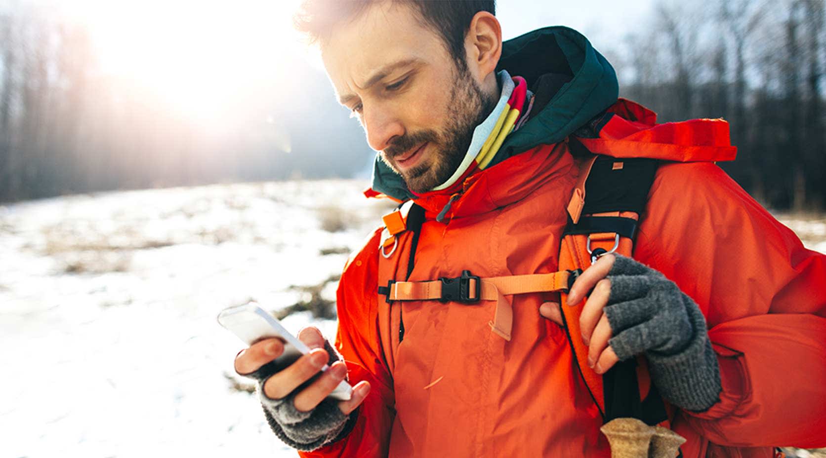 Mann im Schneeanzug schaut aufs Handy