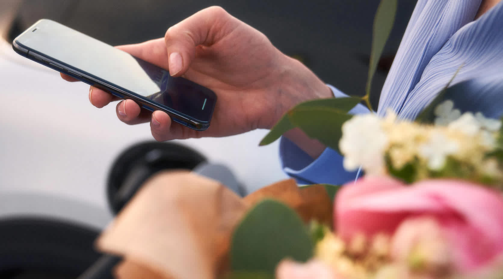Frau steht am E-Auto und hält ihr iPhone in der Hand
