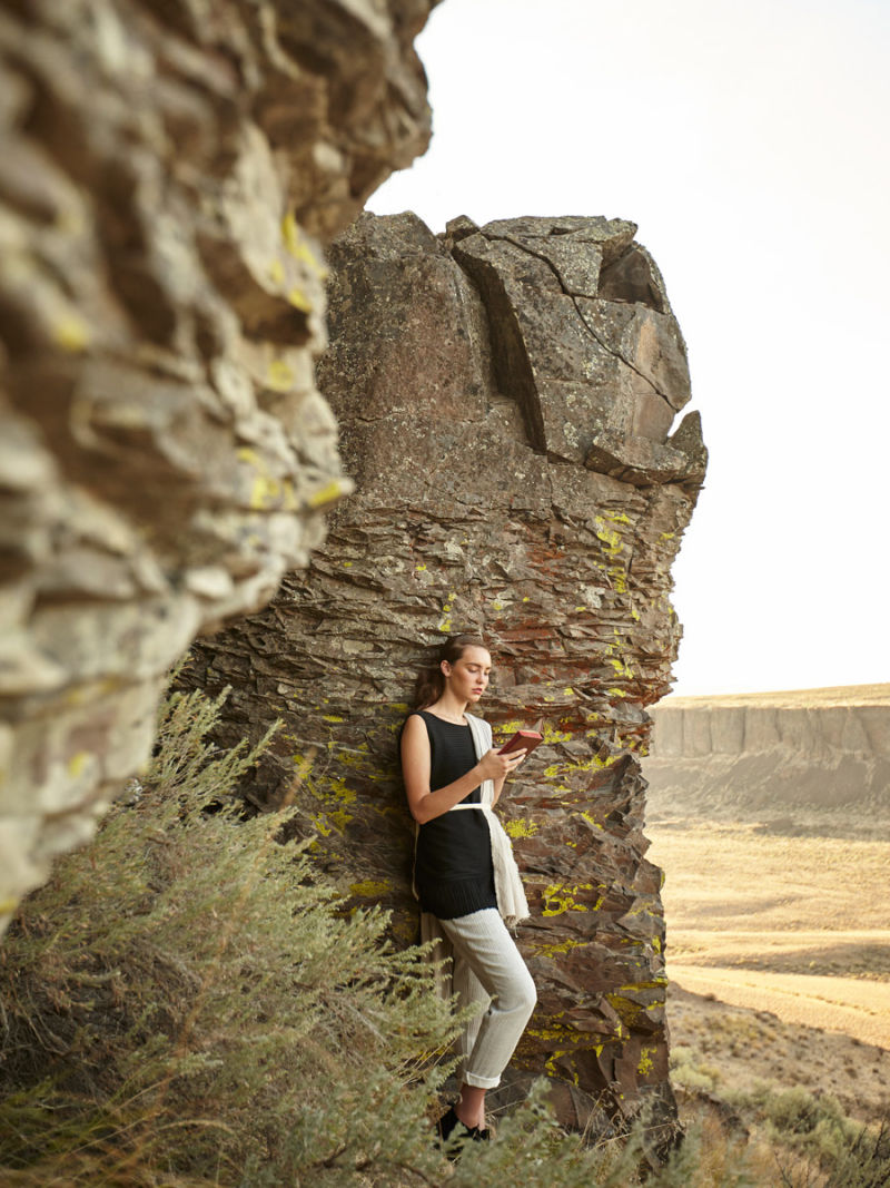 Woman leaning against a rock reading a book