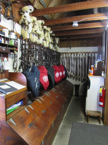 A well organized and clean tack room with cubbies, tack hooks, and paperwork.