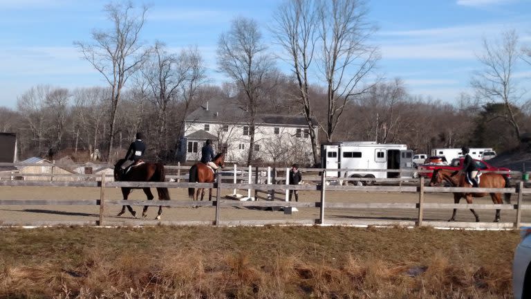 Horses and riders in an outside schooling ring at a hunter jumper horseshow.