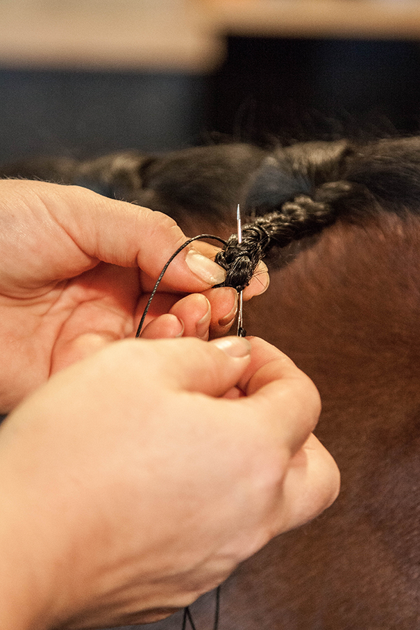 Needle and thread sewn into the bottom of a button braid.