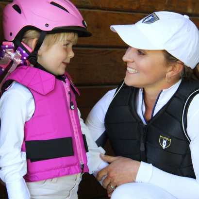 Mother and daughter wearing safety riding vests.