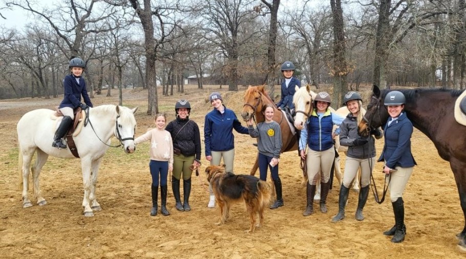 Group of English horseback riders wearing helmets with horses and a dog