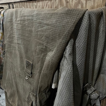 A dusty fly blanket, folded over a blanket bar.