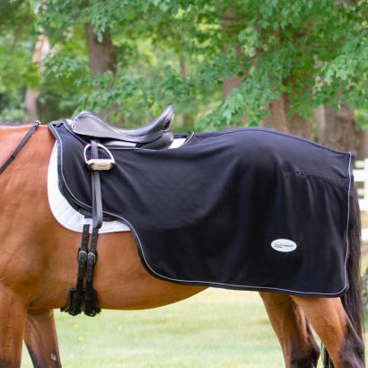 A dressage horse wearing a ceramic fleece quarter sheet under saddle. 
