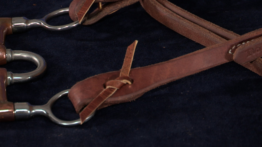 A single knot tie attaching the bit onto the cheek piece of a western headstall.