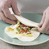 Fold bottom and side edges in, then roll omelet and tortilla together.