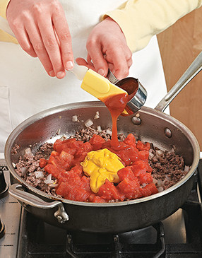 Add the canned tomatoes and condiments, stirring until they're incorporated and heated through.