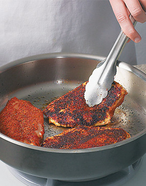 Season chicken breasts by rubbing Cajun spice all over them; cook in oil until crusted and cooked through.